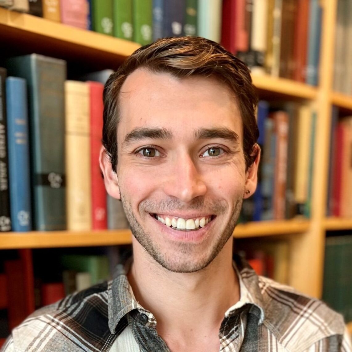 A portrait of Greggory Heller in a library