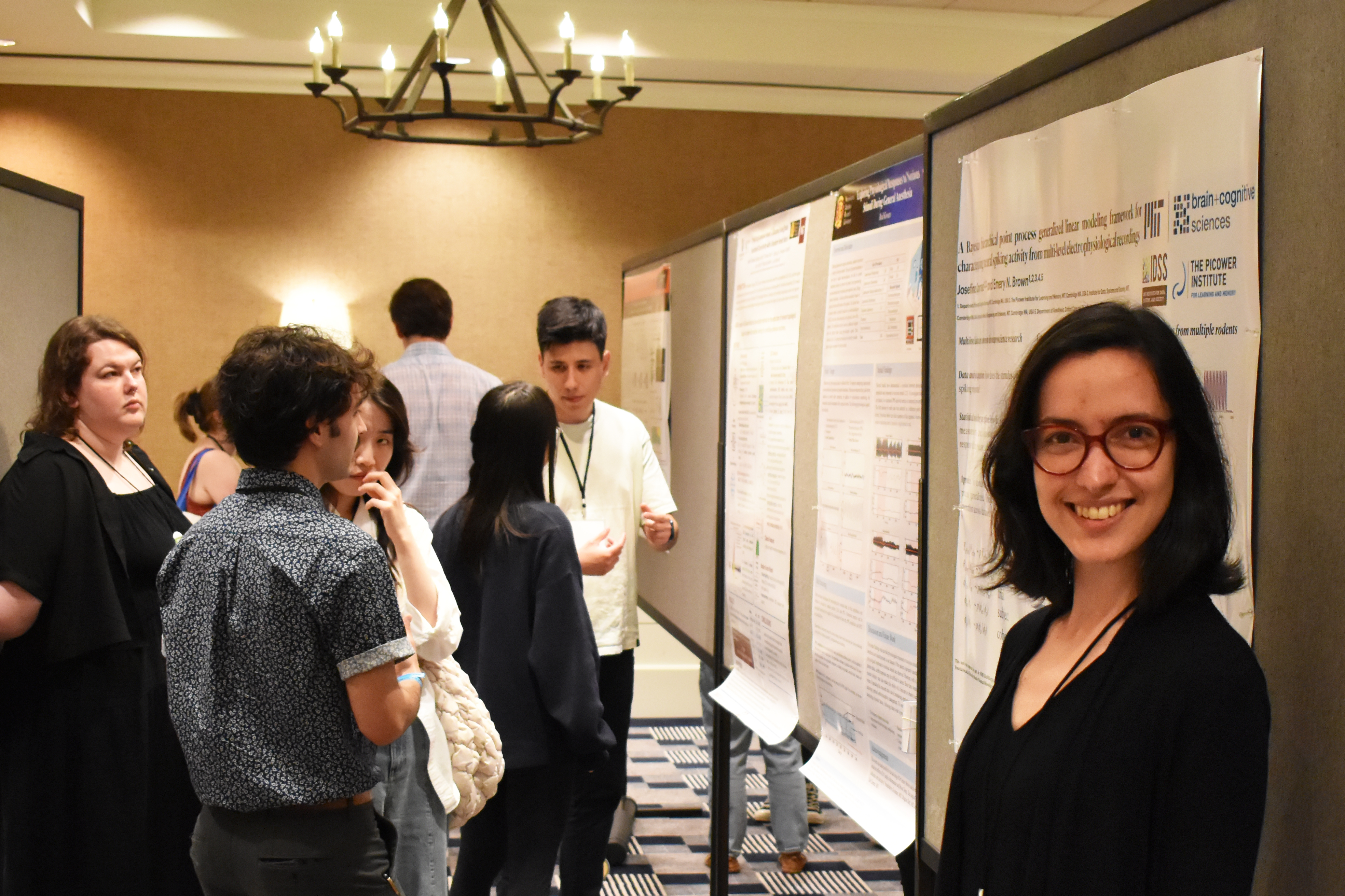 Josefina Correa Menendez stands at her research poster with other posters and onlookers in the background.