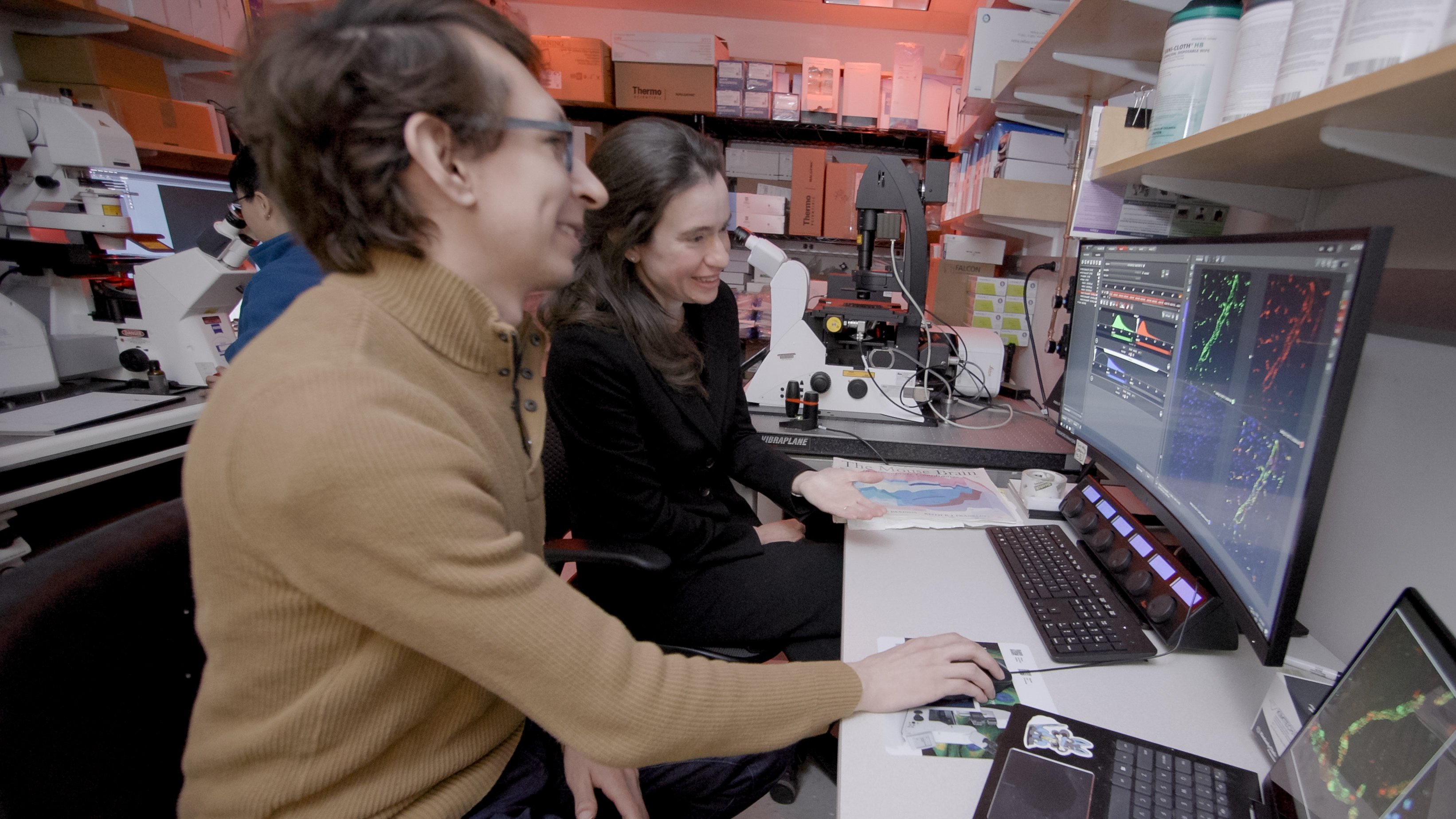 Francisco Garcia and Myriam Heiman sit at a large curved monitor displaying colorful images of blood vessels