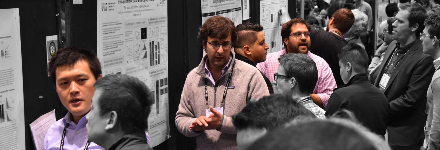 Several scientists stand before posters explaining them to onlookers