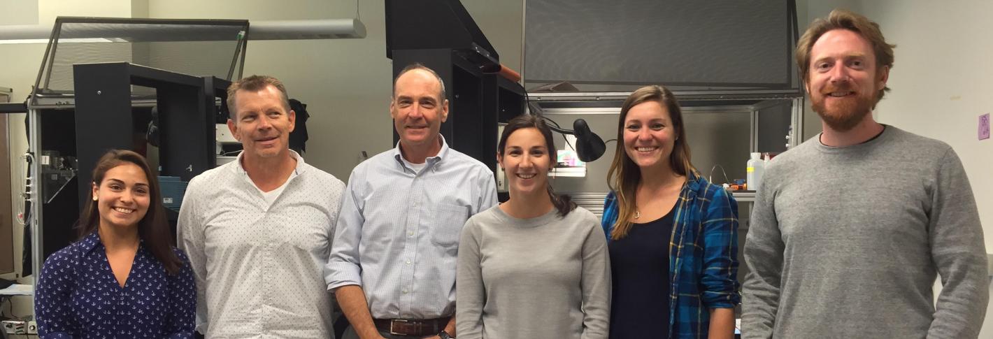 Six researchers in the Bear lab stand shoulder to shoulder in a line