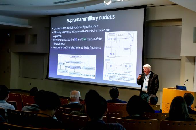 Thomas McHugh presents a slide on the supramammillary nucleus as the audience looks on